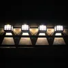 Four solar-powered wall lights mounted on a dark surface at night, casting triangular shadows. Podgląd zdjęcia produktu