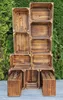 A stack of wooden crates arranged in a display against a green hedge background. Náhled obrázku produktu