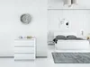 A minimalist bedroom with a white dresser and a white bed. Produktbild-Vorschau