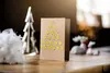 A Christmas card decorated with gold stars in the shape of a Christmas tree, placed on a wooden surface with other festive decorations in the background. Produktbild-Vorschau