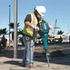 A construction worker using a jackhammer on a paved surface. Anteprima dell’immagine prodotto