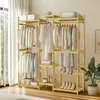 A wooden wardrobe stand with clothes hanging on it, placed in a room with natural light coming from a window. Náhled obrázku produktu