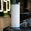 A close-up shot of a white pool filter cartridge with blue ends, resting on the edge of a dark hot tub. Produktbild-Vorschau