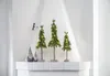 Three decorative LED Christmas trees and two gnomes are displayed on a white shelf against a white wall. Produktbild-Vorschau