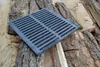 A cast iron grate rests on a pile of logs. Anteprima dell’immagine prodotto