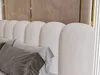 A close-up view of a beige upholstered headboard with decorative pillows in front of it. Produktbild-Vorschau
