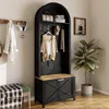 A hallway or entryway scene featuring a black hall tree with a wooden bench seat, hooks, and shelves, along with a green upholstered bench and a potted plant. Produktbild-Vorschau