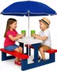 Two children are sitting at a picnic table with an umbrella, holding cups. Anteprima dell’immagine prodotto