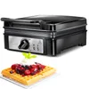 A black waffle maker is shown above a freshly made waffle topped with berries and whipped cream. Produktbild-Vorschau