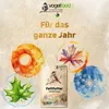 A bag of bird food is surrounded by watercolor illustrations of leaves representing different seasons, with text promoting year-round use. Produktbild-Vorschau