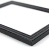 A close-up, angled view of a black picture frame against a white background. Produktbild-Vorschau