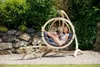 A young woman relaxing in a hanging chair in a garden setting. Produktbild-Vorschau