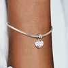 A close-up shot of a silver Pandora bracelet with a heart-shaped charm on a person's arm. Náhled obrázku produktu