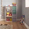 A child's room with a white shelving unit filled with toys and books, against a blue and white checkered wallpaper. Produktbild-Vorschau
