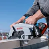 A person is using a Bosch cordless circular saw to cut a piece of wood outdoors. Podgląd zdjęcia produktu