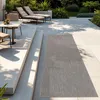 An outdoor patio scene with lounge chairs, a table and chairs, and a rug. Produktbild-Vorschau