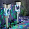 Two solar-powered garden lights are shown in a garden setting at night, projecting colorful lights onto the ground and a wall. Anteprima dell’immagine prodotto