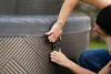 Two people are shown securing the cover of an inflatable hot tub outdoors. Náhled obrázku produktu
