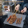 A person is using a portable grill table outdoors, cooking food on skewers. Náhled obrázku produktu