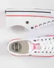 A close-up view of two white canvas sneakers with red and blue accents. Produktbild-Vorschau