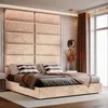 A modern bedroom featuring a large, upholstered headboard and a bed with several pillows and a throw blanket. Anteprima dell’immagine prodotto
