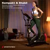 A woman is exercising on a Sportstech crosstrainer in a living room setting with a dog on the couch. Produktbild-Vorschau