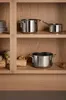 Stainless steel pots are neatly arranged on wooden shelves in a cabinet. Náhled obrázku produktu