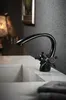 A close-up shot of a black faucet in a bathroom sink. Anteprima dell’immagine prodotto