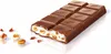 A chocolate bar with a bite taken out, showing its creamy filling and cereal pieces, with some hazelnuts scattered nearby. Náhľad obrázku produktu