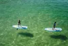 Two people stand on paddleboards in clear, green water. Produktbild-Vorschau