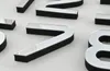 A close-up view of several metallic numbers with black foam bases, arranged on a white surface. Anteprima dell’immagine prodotto