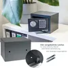 Two safes are shown on a white shelf, with a plant in the background. One safe is open, revealing its electronic lock and keypad. A close-up inset shows the mounting holes and hardware for securing the safe. Text describes the pre-drilled holes for wall or Anteprima dell’immagine prodotto