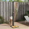 An outdoor shower set up on a wooden deck next to a wooden fence, with plants and a lounge chair in the background. Voir les images du produit