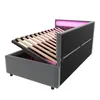 A bed frame with its mattress support raised, showing the storage space underneath. Pink LED lighting is visible along the headboard. Anteprima dell’immagine prodotto