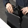 A person is placing a laptop charger into a black bag. Produktbild-Vorschau