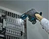 A person wearing gloves is using a cordless flashlight to illuminate an electrical panel. Podgląd zdjęcia produktu