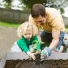 A father and daughter are planting a small plant in a garden bed. Náhled obrázku produktu