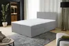 A bedroom scene featuring a gray boxspring bed with a white mattress and headboard. A large plant is visible in the background, along with a closet and a floor lamp. Voir les images du produit