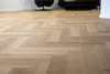 A close-up view of a herringbone wood floor. Produktbild-Vorschau
