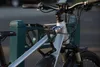 A close-up shot of an electric bicycle locked to a green post. Náhled obrázku produktu