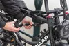 A person is locking a bicycle to a pole with a folding lock. Produktbild-Vorschau