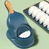 A blue and orange dumpling maker is shown on a light green background, with several finished dumplings on a tray in the background. Podgląd zdjęcia produktu