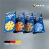 Four packages of VARTA hearing aid batteries are displayed diagonally against a light gray background. The packages are blue and feature the VARTA logo and product information. Each package contains a different color of hearing aid batteries arranged in a  Voir les images du produit