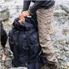 A person is packing a large black backpack in an outdoor, rocky environment. Náhľad obrázku produktu