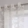 A close-up view of sheer curtains with an ornate pattern hanging from a curtain rod. Produktbild-Vorschau