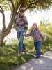 A woman and a child walking hand-in-hand on a path in a park. Produktbild-Vorschau