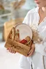 A person holding a wooden basket filled with items, including a plate, spices, and dried plants. Produktbild-Vorschau