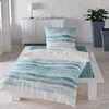 A bed with bedding in a room with a dresser and plants. Produktbild-Vorschau