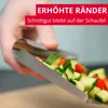 A hand holding a metal scoop filled with chopped vegetables. Produktbild-Vorschau