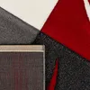 A close-up view of a rug with geometric patterns in red, gray, and white. The backing of the rug is also visible. Anteprima dell’immagine prodotto
